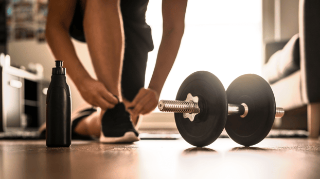 man bending down to tie shoelace with a weight in front man bending down to tie shoelace with a weight in front