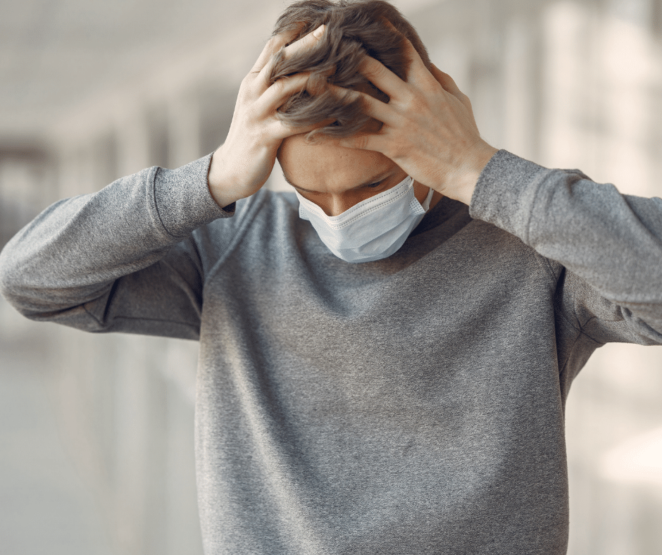 Man wearing a mask and holding his head